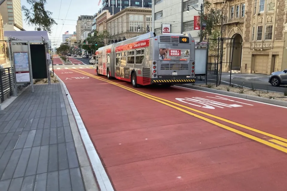 Red bus only lanes on Van Ness Avenue in San Francisco, California with bus stopped at station.